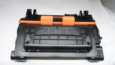 A black and orange toner cartridge is shown against a white background.