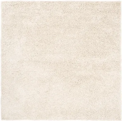 A close-up, top-down view of a square, beige rug with a shaggy texture.
