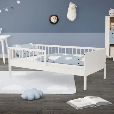 A child's bed with bedding and a rug in a room.