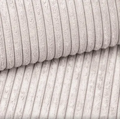 A close-up view of beige corduroy fabric, showing the texture and ribbed pattern.