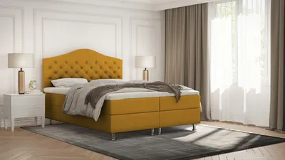 A bedroom scene with a yellow boxspring bed, nightstands, and lamps.