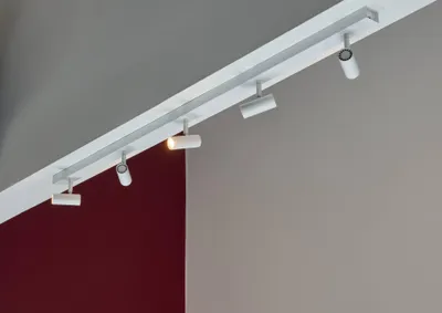 A white track lighting system with multiple adjustable LED spotlights mounted on a ceiling.
