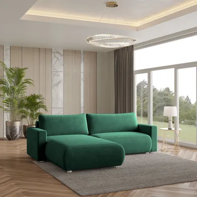 A modern living room with a green sectional sofa, plants, and a large window.