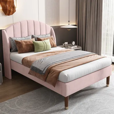 A pink upholstered bed with pillows and a blanket in a bedroom setting.