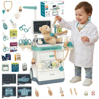 A child dressed as a doctor plays with a medical trolley toy.