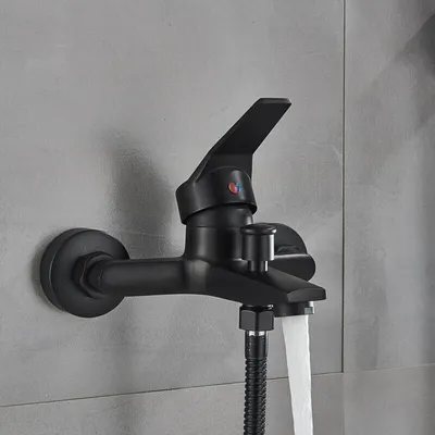 A black bathtub faucet with water flowing from it, mounted on a gray tiled wall.