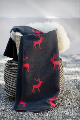 A dark gray blanket with a red deer pattern is draped over a basket.