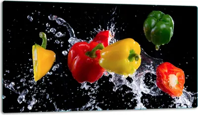 Several bell peppers are shown in mid-air with water splashing around them against a black background.