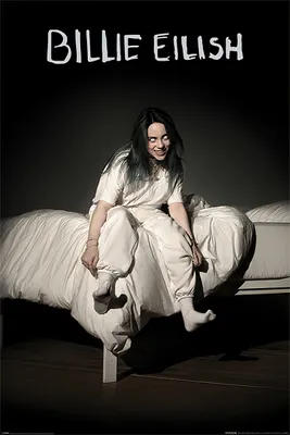 Billie Eilish sitting on a bed with white sheets.