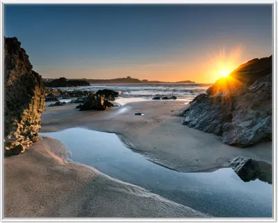 Produktbild von Wallario Wandbild Sonnenuntergang hinter einem Felsen am Strand, Größe: 40,30 x 50,30 cm, Poster mit weißem Aluminiumrahmen