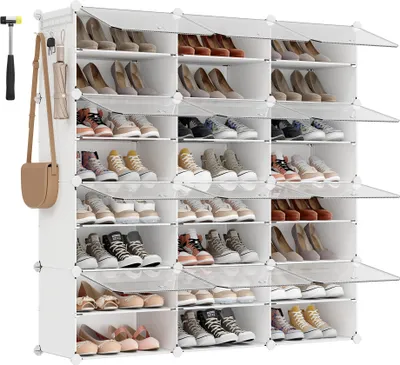 A multi-tiered white shoe rack filled with various shoes, with a purse and umbrella hanging on the side.