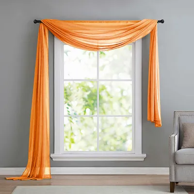 An orange sheer scarf draped over a window.