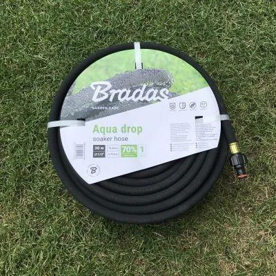 A coiled black soaker hose is laid out on a grassy lawn.