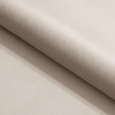 A close-up view of beige fabric, likely upholstery or bedding, with a soft texture and a gentle curve.