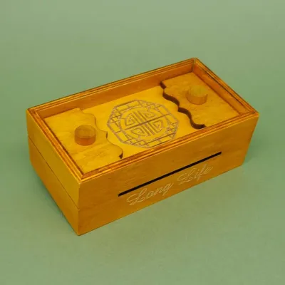 Long Life‘-Holzschatulle mit Ornament; rechteckige, honigfarbene Box mit Schlitz und zwei runden Knäufen auf dem Deckel.