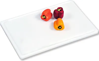 Three small bell peppers on a white cutting board.