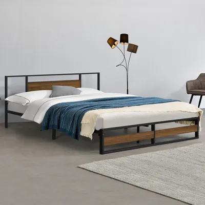 A bed frame with a headboard and bedding in a room.