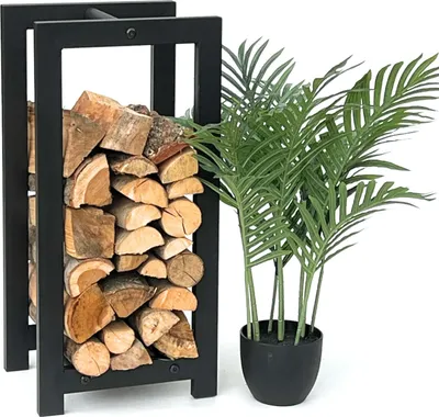 A black metal firewood rack filled with logs next to a potted green plant.