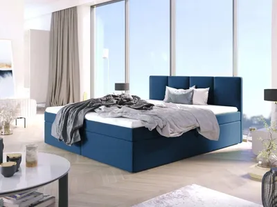 A bedroom scene with a large blue bed in the center, positioned in front of a large window with a view of the sky.