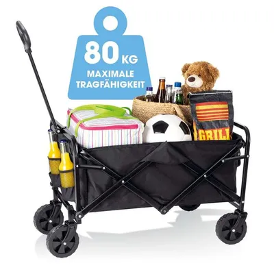 A black foldable wagon filled with various items for an outing, including a cooler, drinks, a teddy bear, a soccer ball, and grilling supplies.