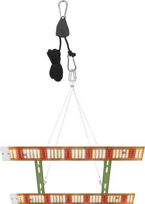 A grow light panel suspended by a pulley system against a white background.