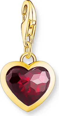 A gold charm with a red heart-shaped gemstone.
