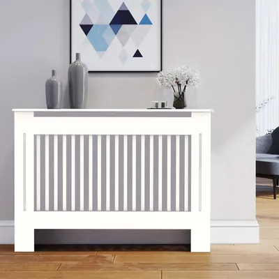 A white radiator cover with vertical gray slats is shown in a room setting, with decorative vases and a framed picture on top.