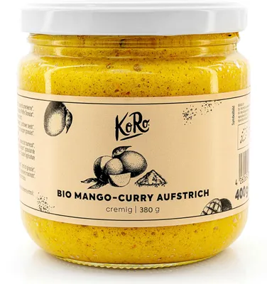 A glass jar of mango-curry spread on a white background.