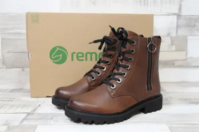 A pair of brown leather boots are displayed in front of their packaging box.