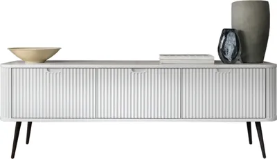 A white TV cabinet with fluted fronts and black legs, decorated with a bowl and two vases.