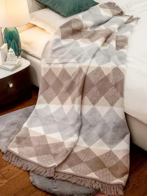 A blanket draped over a bed, with a bedside table and lamp visible.