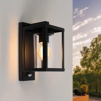 An outdoor wall light mounted on a wall, with trees and sky in the background.