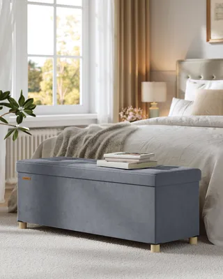 A bedroom scene with a storage bench in the foreground and a bed in the background.