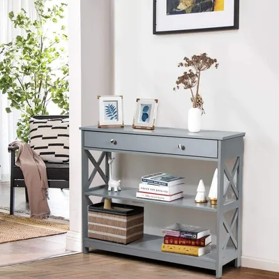 A gray console table with decorative items and books is shown in a room.