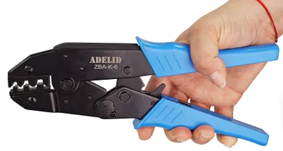 A hand holding a crimping tool.