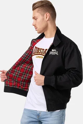 A man wearing a black Lonsdale jacket with a red plaid lining and a white Lonsdale t-shirt.