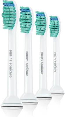 Four white electric toothbrush heads with green and blue bristles are arranged in a row against a white background.