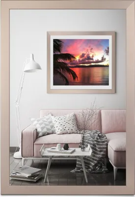 A living room scene featuring a pink sofa, a coffee table with decorative items, and a floor lamp, with a framed picture of a sunset hanging on the wall.