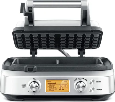 A silver and black waffle maker with its lid open, displaying the waffle grid.