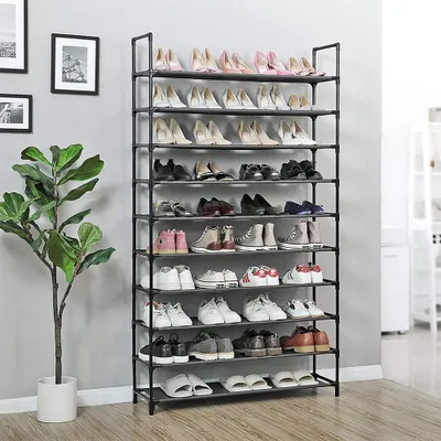 A multi-tiered shoe rack filled with shoes, placed next to a tall potted plant against a light gray wall.