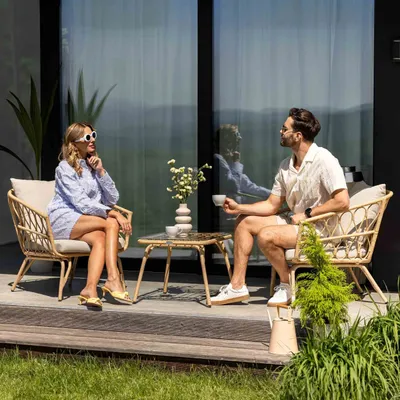 A couple enjoying coffee on a patio, seated in rattan chairs.
