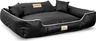 A black dog bed with white trim and two small pillows, shown from a slightly elevated side angle on a white background.