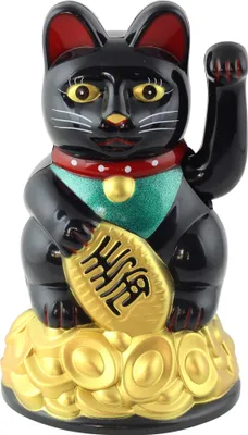 A black lucky cat figurine sitting on a pile of gold coins.