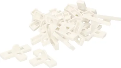 A pile of white plastic tile spacers on a white background.