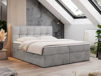 A modern bedroom with a boxspring bed in a loft setting with skylights.