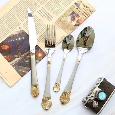 A set of cutlery laid out on a newspaper.