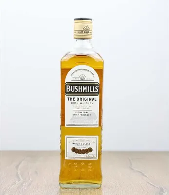 A bottle of Bushmills Original Irish Whiskey on a wooden surface.