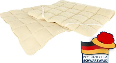 Two quilted cream-colored mattress toppers are shown on a white background. A German flag with a hat and text is in the bottom right corner.