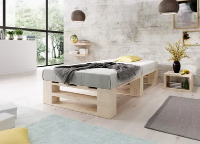 A bedroom with a wooden pallet bed, bedding, and decorative items.