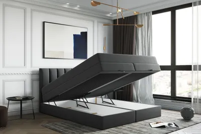 A dark gray boxspring bed with its storage compartment open, shown in a bedroom setting.